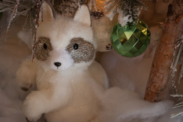 Plush raccoon under Christmas tree.