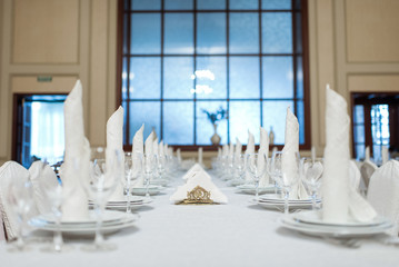 Festive table setting of the wedding table with crystal glasses and pink and white napkins