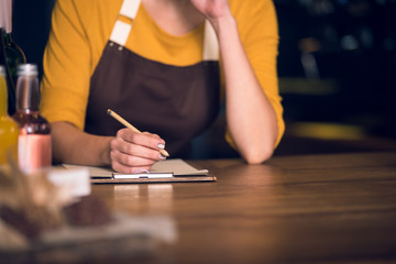 Close up female hand writing information on paper by pencil. She resting elbow on table. Occupation...