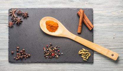 Специи на каменной доске на деревянном фоне