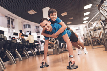 Fototapeta na wymiar Dad and son in the same clothes in gym. Father and son lead a healthy lifestyle.