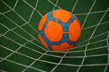 Football in goalpost against artificial grass