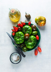different kinds of tomatoes on a plate on a white stone table. fresh ripe ingredients for a healthy diet. proper nutrition