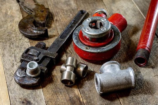Hydraulics, tools for plumber on wooden table. Workshop, table and tools - adjustable spanner, connectors, keys.
