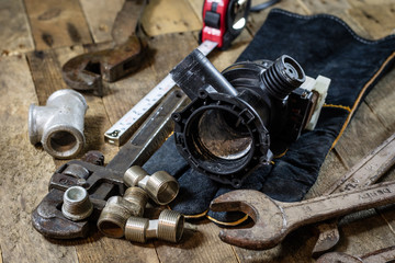 Hydraulics, tools for plumber on wooden table. Workshop, table and tools - adjustable spanner, connectors, keys.