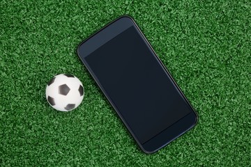 Football and mobile phone on artificial grass