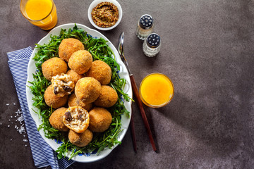 Italian snack. Fried balls from rice Arancini with mushrooms, cheese with mustard sauce and a salad of rucola on a gray stone table with freshly squeezed orange juice. fast healthy hearty meal