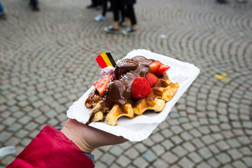 Belgium waffle with chocolate sauce and strawberries, Bruges city background