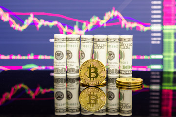 Golden bitcoin and rolled dollar bills on stock market chart background
