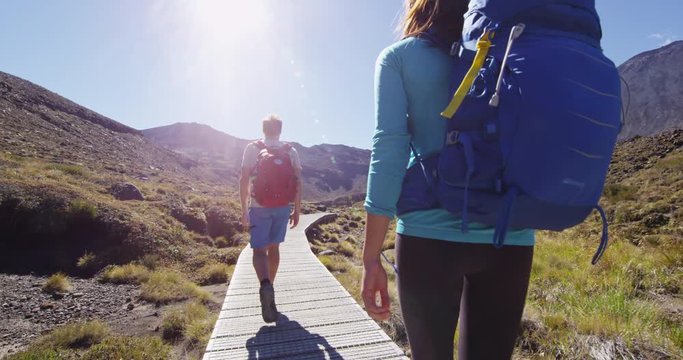 Adventure - Hiking people tramping on trail in Tongariro Alpine Crossing, a National Park in New Zealand, North Island. Male and female hikers couple hiking by Mount Ngauruhoe. RED EPIC SLOW MOTION.