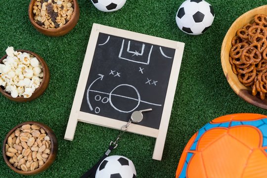 Strategy board, whistle and football on artificial grass