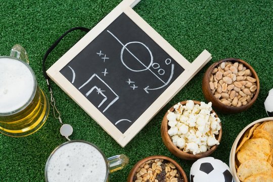 Strategy board, football and snacks on artificial grass