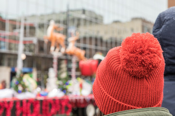 A woman wearing a red hat watching  a Santa Christmas parade