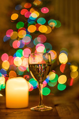 Glass of white wine during holiday season with bright festive bokeh lights