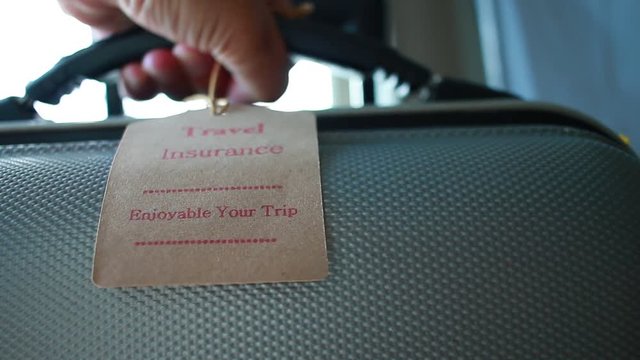 Travel Insurance tag on Suitcase safety with letters enjoyable your trip on bag light blurred background, that is intended cover medical expenses, trip cancellation or flight accident.