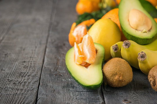 The Mandarin slices inside a half avocado and other tropical fruit on a wooden table.