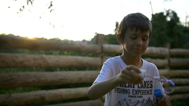 Boy Blowing Soap Bubbles At Sunset