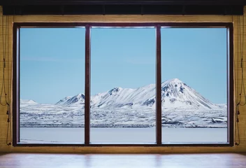 Crédence de cuisine en verre imprimé Hiver Looking through window in winter, wooden window frame with desk and landscape snow mountain and frozen lake view in Iceland