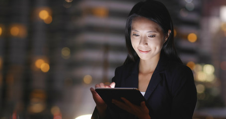 Businesswoman using tablet computer in city at night