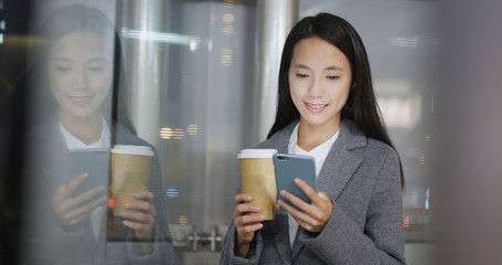 Woman use of mobile phone hold coffee cup