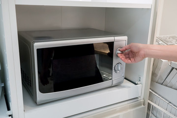 Woman's Hands adjusting heat button on microwave