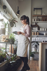Female florist standing in her flower shop using a tablet