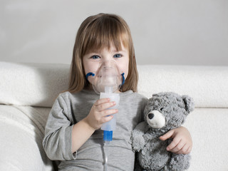 Little girl making inhalation with nebulizer at home. child asthma inhaler inhalation nebulizer...