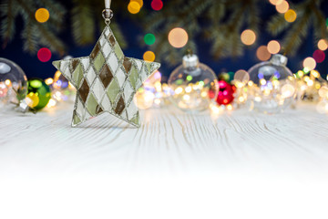 christmas star with transparent glass balls and holiday lights on white wooden background
