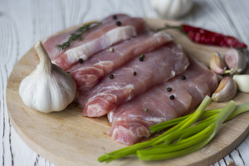 chopped pieces of fresh meat on the Board on the table with herbs and garlic