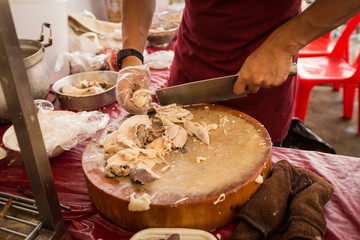 Obraz na płótnie Canvas Chef hand cutting boiled chicken on Chopping board.