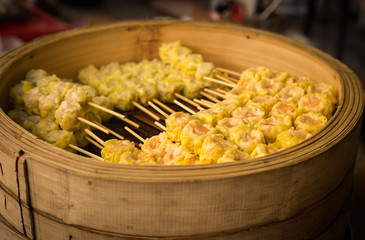 Selective soft focus of Chinese Steamed Dumpling in bamboo basket on market.