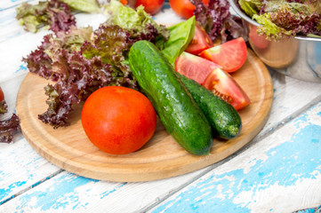 Cutting board with ingredients for salad on the table.