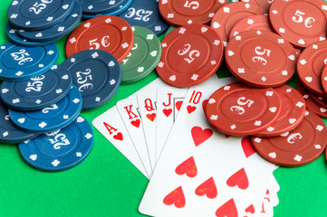Poker chips with playing cards on the green background.