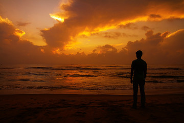 Thoughtful young man standing and watching the sunset. 