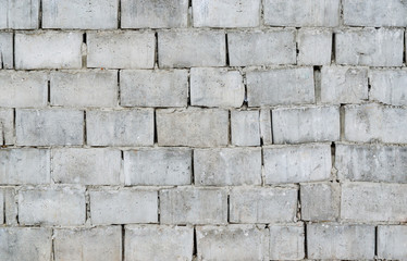 Texture old cracks in the hardened cement gray brick wall, abstract background, close-up