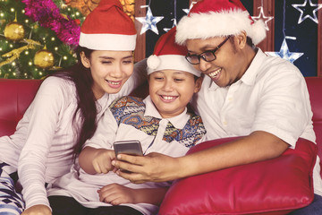 Happy family using a smartphone at Christmas time
