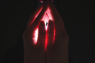 Woman holding light in hands on dark background. Guardian angel protection concept