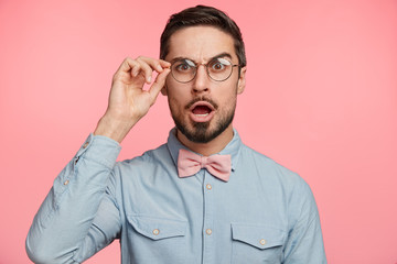 Surprised male manager stares through spectacles, keeps jaw dropped, shocked to see that there...