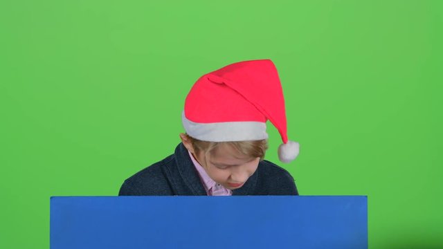 Teenager in the hat appears from a board on a green screen