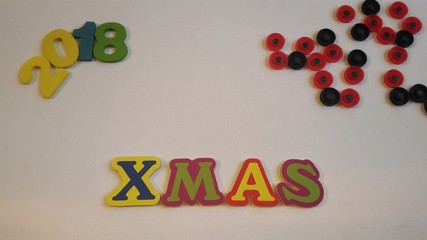 Colored letters spell out Xmas on white canvas with Christmas gifts