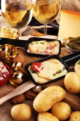Gordijnen Delicious traditional Swiss melted raclette cheese on diced boiled or baked potato served in individual skillets. © beats_