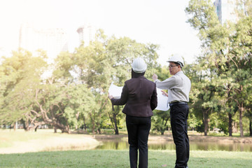 asian men and women engineers work on plans construction  in the park