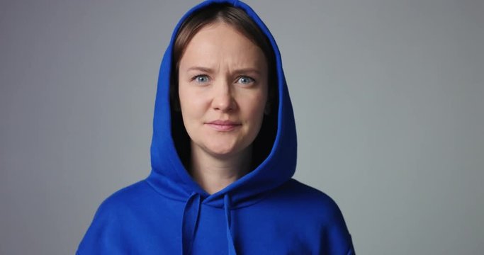 Young woman in large unlabeled bright blue hoodie screams and acts scared and angry isolated on white