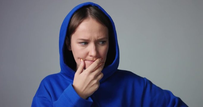 Young woman in large unlabeled bright blue hoodie screams and acts scared and angry isolated on white