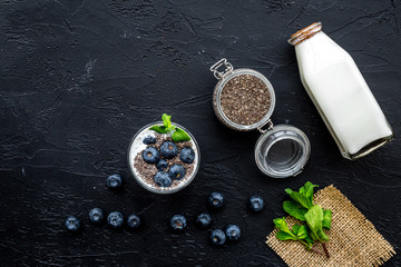 Fototapeta na wymiar Light dessert with chia seeds, yogurt, blueberry and mint. Black background top view copyspace