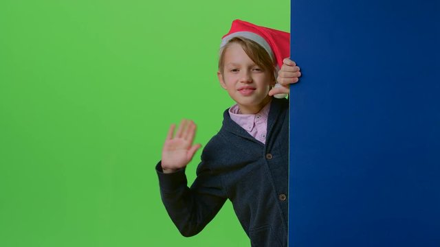 Child boy holding hands on the board appears to her in a christmas hat on a green screen