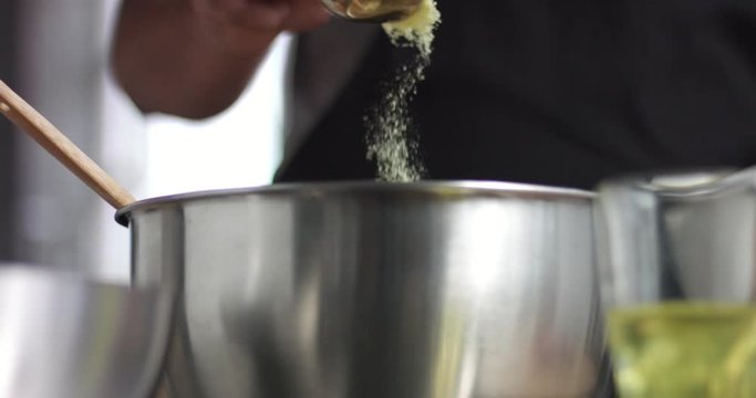 Male chef preparing potato casserole with cheese and olive oil in a large stainless steel bowl