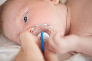 The child lying on the bed sucking on a pacifier