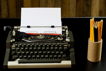 typewriter on the black table. White blank card. Wall of rough boards.