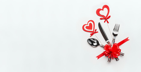 Festive table place setting with cutlery and red ribbon and hearts on white background, banner. Layout for Valentines day dinner invitation or anniversary, banquet, celebration, event
